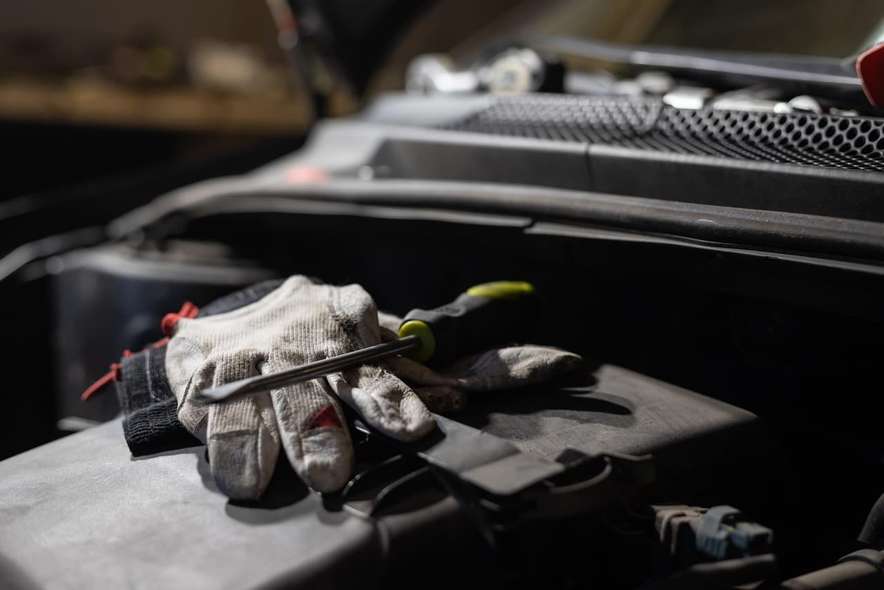 Arbeitshandschuhe und Werkzeug für die Prüfung des Motorraums